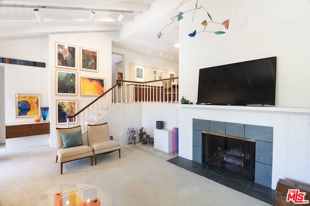 living room featuring beamed ceiling, high vaulted ceiling, track lighting, a fireplace, and carpet