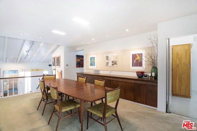 dining space featuring lofted ceiling with beams and light colored carpet