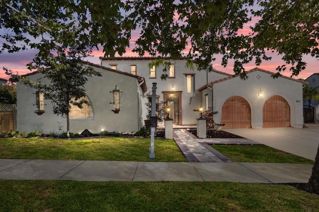 mediterranean / spanish-style house with a lawn and a garage