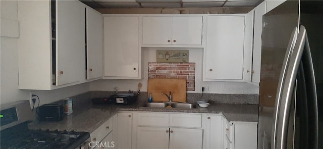 kitchen featuring stainless steel fridge, white cabinets, sink, and range