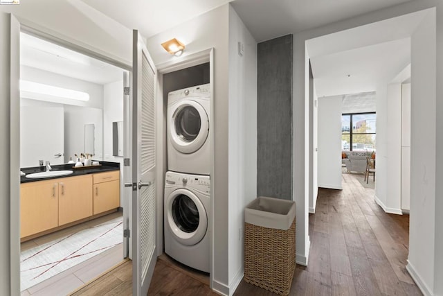 washroom with wood-type flooring, stacked washer / dryer, and sink