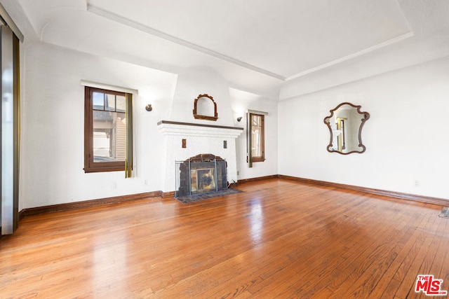 unfurnished living room featuring a tray ceiling and light hardwood / wood-style flooring