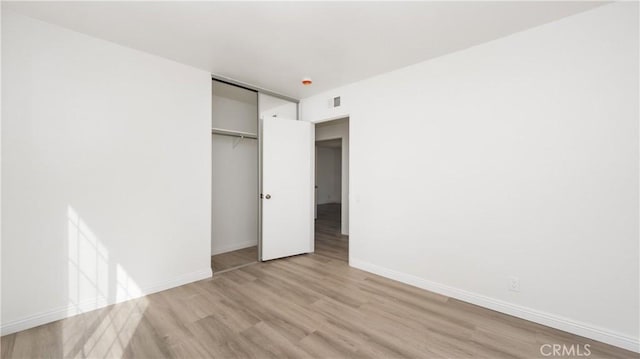 unfurnished bedroom with light hardwood / wood-style floors and a closet