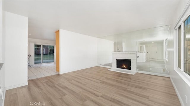 unfurnished living room with light hardwood / wood-style floors and a brick fireplace