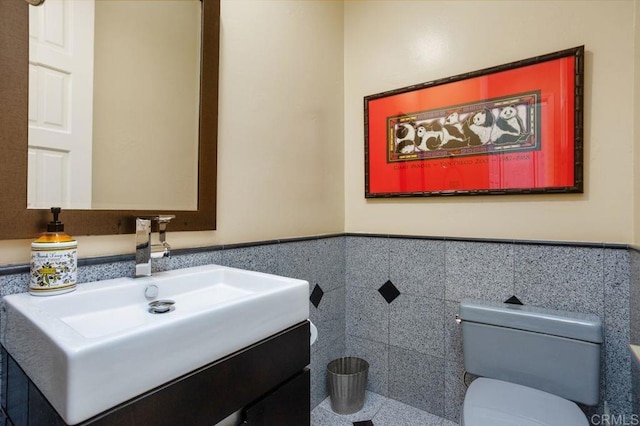 bathroom featuring vanity, toilet, and tile walls