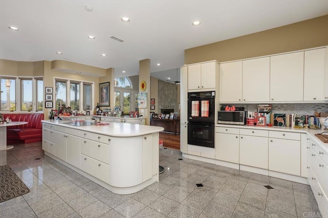 kitchen featuring white cabinets, sink, double oven, tasteful backsplash, and a kitchen island