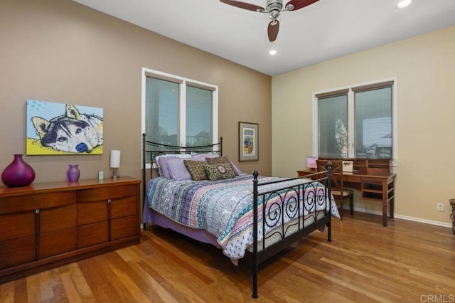 bedroom with ceiling fan, multiple windows, and light hardwood / wood-style flooring