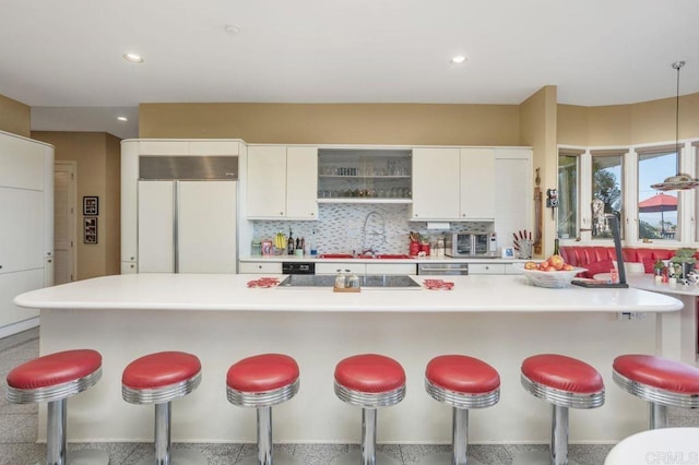 kitchen with a kitchen breakfast bar, tasteful backsplash, sink, paneled built in fridge, and white cabinets