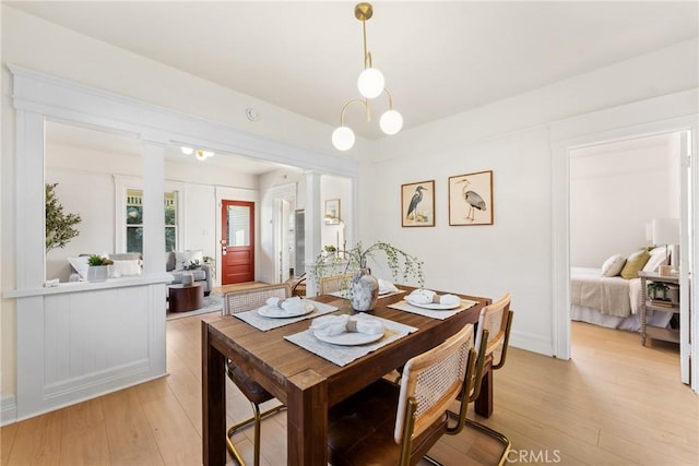 dining space with light wood-type flooring and ornate columns