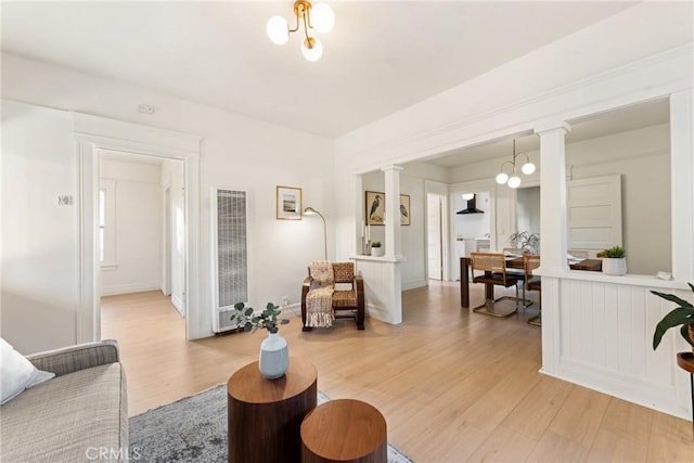 living room with hardwood / wood-style floors, decorative columns, and a chandelier