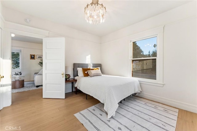 bedroom featuring an inviting chandelier and light hardwood / wood-style flooring