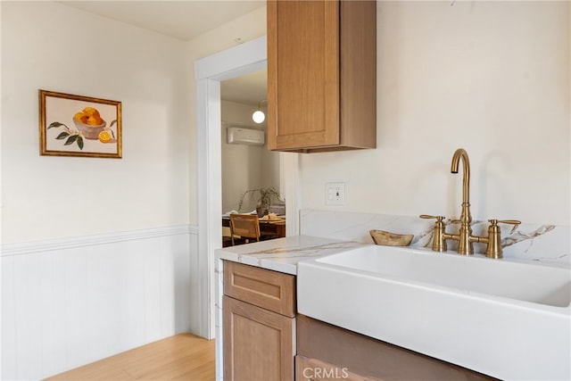 kitchen with light hardwood / wood-style floors, a wall unit AC, and sink