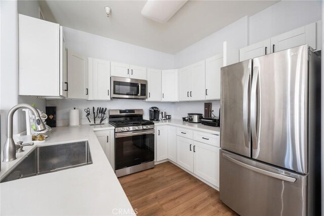 kitchen with sink, white cabinets, stainless steel appliances, and light wood-type flooring