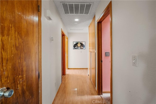 hall featuring a textured ceiling and light wood-type flooring