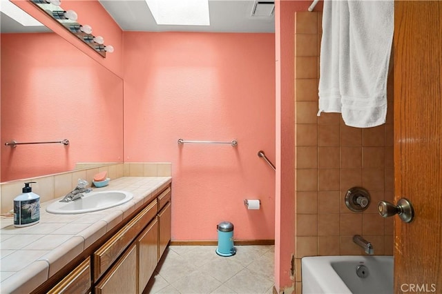 bathroom with vanity, tiled shower / bath, and a skylight