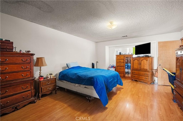 bedroom with a textured ceiling and light hardwood / wood-style flooring