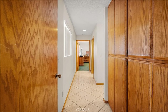 corridor featuring light tile patterned flooring and a textured ceiling