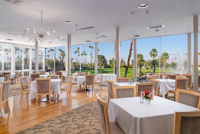 dining space with a wealth of natural light, a chandelier, expansive windows, and light hardwood / wood-style floors