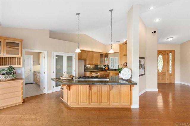 kitchen featuring light wood-type flooring, stainless steel gas cooktop, kitchen peninsula, light brown cabinets, and lofted ceiling