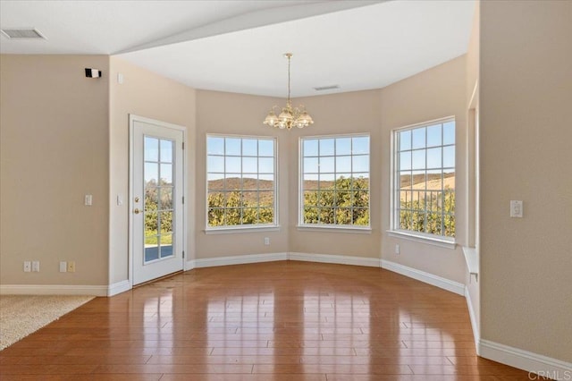 unfurnished dining area with a notable chandelier, a mountain view, and wood-type flooring