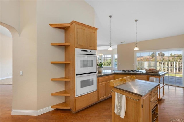 kitchen with decorative light fixtures, a center island, light hardwood / wood-style floors, light brown cabinetry, and double oven