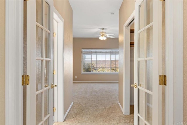 corridor with light colored carpet and french doors