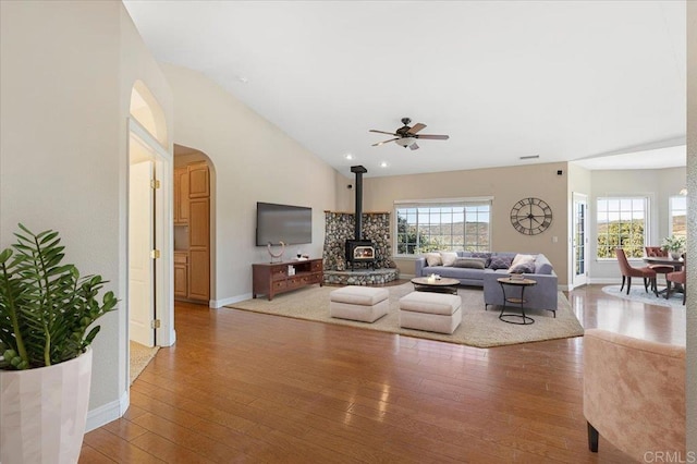 living room with ceiling fan, hardwood / wood-style floors, a wealth of natural light, and a wood stove