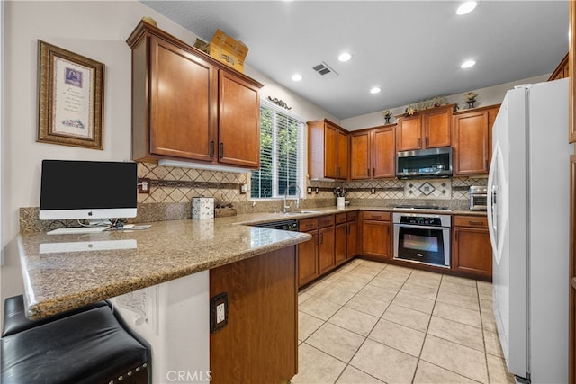 kitchen featuring kitchen peninsula, sink, light tile patterned flooring, appliances with stainless steel finishes, and light stone counters