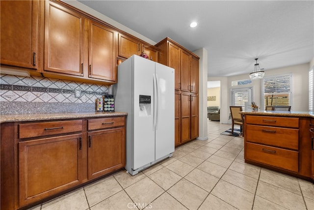 kitchen featuring light tile patterned floors, white refrigerator with ice dispenser, backsplash, and pendant lighting