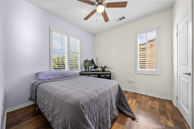 bedroom featuring ceiling fan, multiple windows, and dark hardwood / wood-style floors