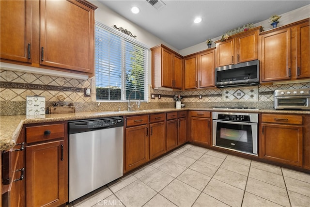 kitchen featuring appliances with stainless steel finishes, light stone countertops, sink, and light tile patterned floors