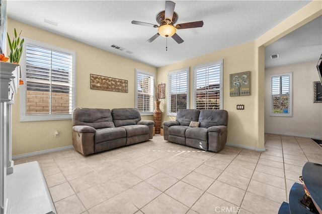 living room featuring ceiling fan, light tile patterned flooring, and plenty of natural light