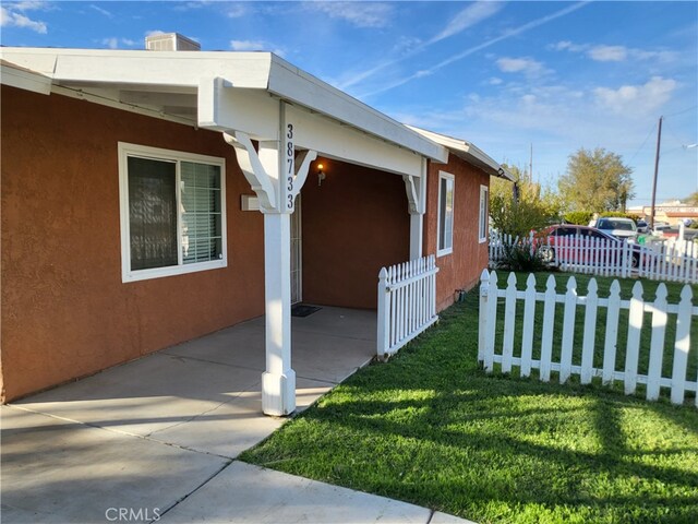 view of side of home featuring a patio area and a lawn