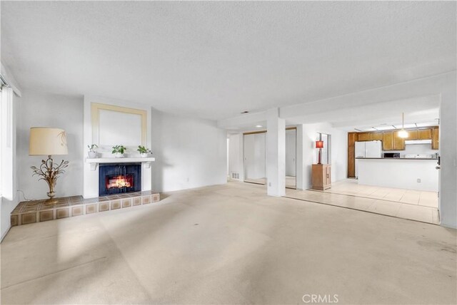 unfurnished living room featuring light carpet and a tiled fireplace