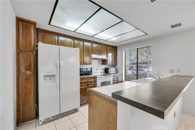 kitchen featuring light tile patterned floors, sink, kitchen peninsula, and white appliances