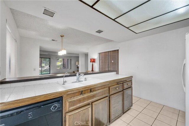 kitchen with tile countertops, sink, black dishwasher, hanging light fixtures, and light tile patterned floors