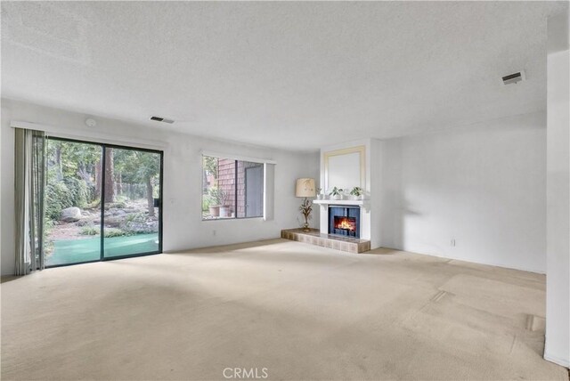 unfurnished living room with light carpet and a textured ceiling