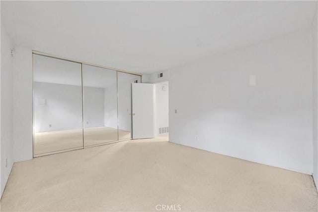 unfurnished bedroom featuring light colored carpet and a closet