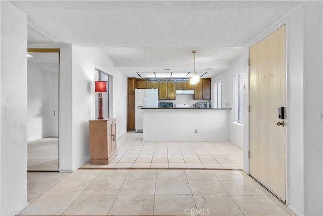 kitchen with kitchen peninsula, light tile patterned flooring, white fridge with ice dispenser, and pendant lighting