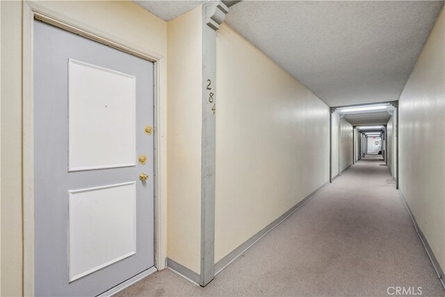 corridor featuring a textured ceiling and light colored carpet