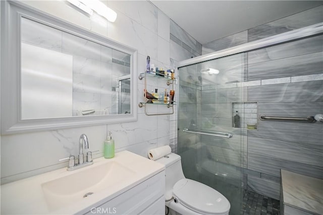 bathroom with vanity, tasteful backsplash, toilet, and a shower with door