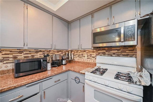 kitchen featuring decorative backsplash, gray cabinets, and white gas stove