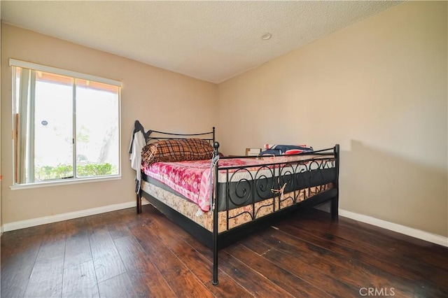 bedroom with dark hardwood / wood-style flooring and a textured ceiling