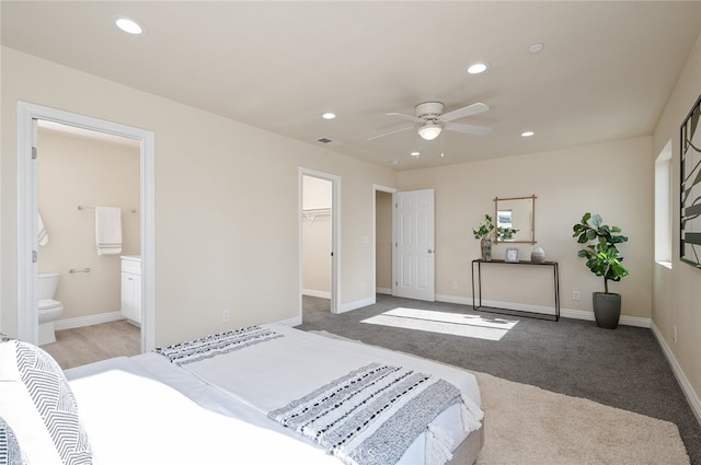 carpeted bedroom with a closet, a spacious closet, connected bathroom, and ceiling fan