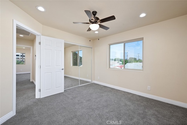 unfurnished bedroom featuring a closet, ceiling fan, and dark carpet