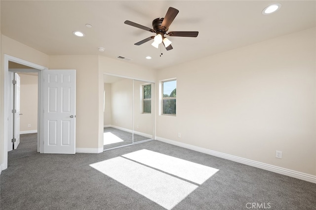 unfurnished bedroom with a closet, dark carpet, and ceiling fan