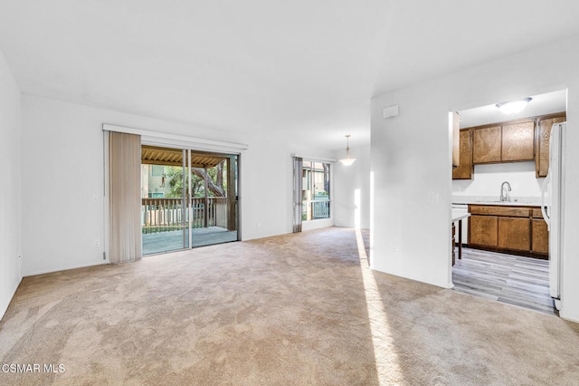 unfurnished living room with sink and light colored carpet