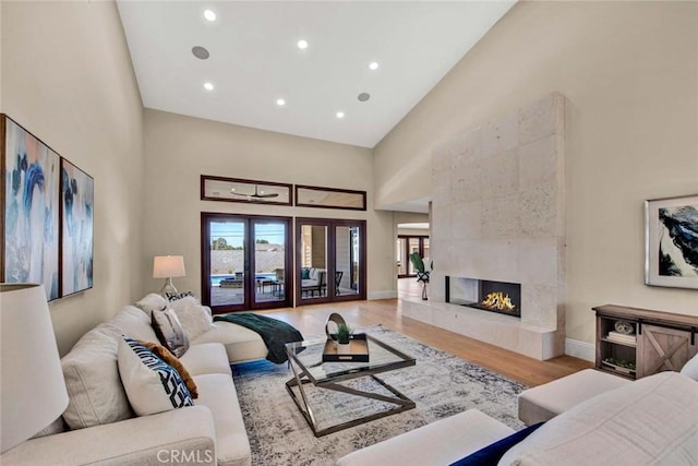 living room featuring a tiled fireplace, hardwood / wood-style floors, and high vaulted ceiling