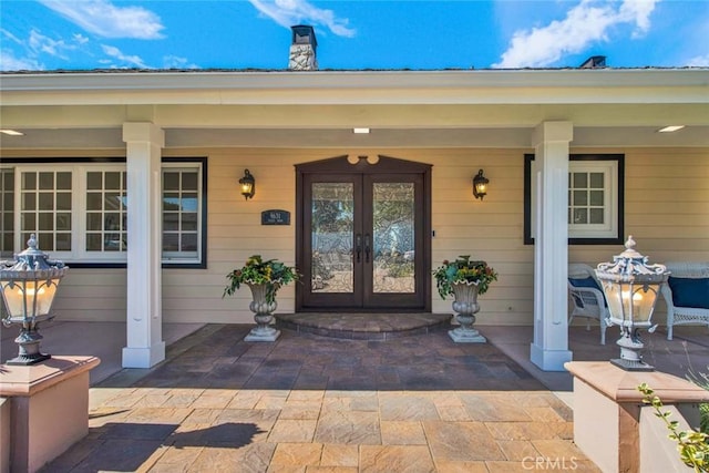 property entrance featuring covered porch and french doors