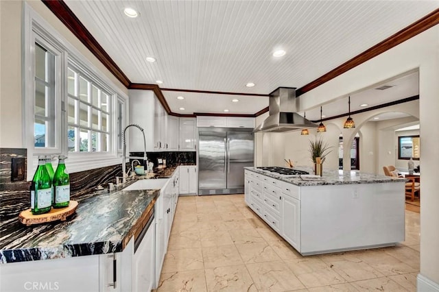 kitchen featuring decorative backsplash, appliances with stainless steel finishes, an island with sink, and wall chimney range hood